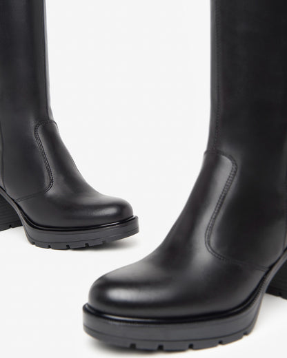 Der elegante Langschaftstiefel von NeroGiardini überzeugt durch seine schlichte Raffinesse und hochwertige Verarbeitung. Komplett aus feinstem Leder gefertigt, bietet er einen angenehmen Tragekomfort – auch bei längeren Tragezeiten. Der 8 cm hohe Blockabsatz streckt optisch das Bein und sorgt dennoch für sicheren Stand. Der praktische Reißverschluss an der Innenseite erleichtert das An- und Ausziehen. Perfekt für stilvolle Herbst- und Winteroutfits!